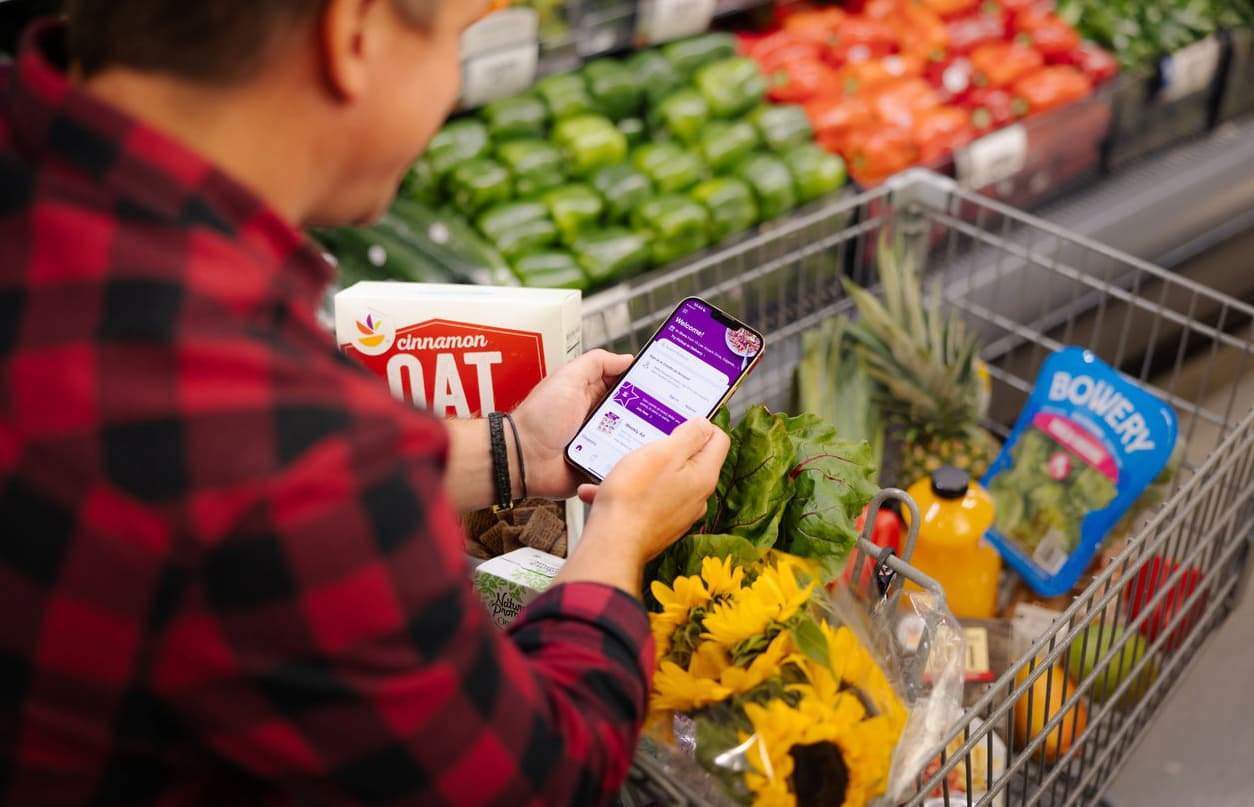 A man holding a phone in front of a shopping trolley