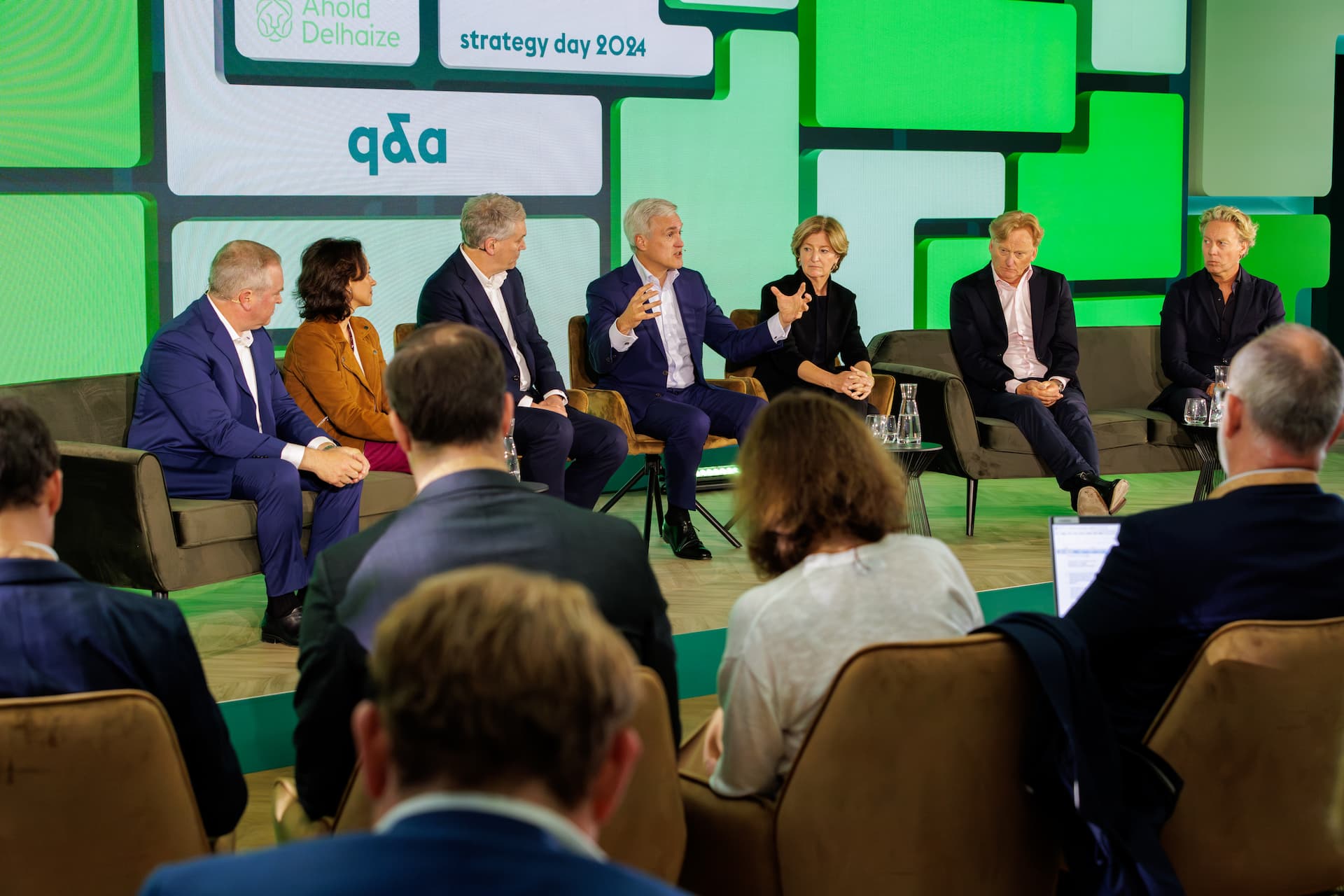 a panel of people sitting on chairs talking to an audience