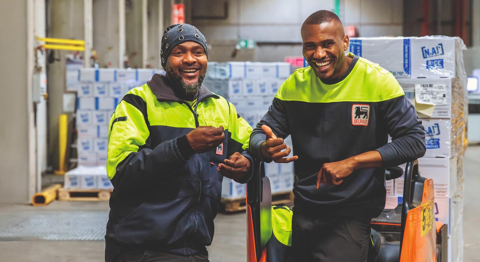 Two men working in the back of a supermarket smiling for the camera